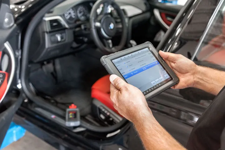 Technician programming a car with a diagnostic tablet